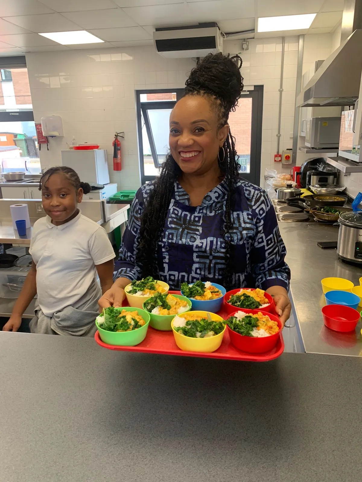 Duchess Nena with a young student and bowls of salad in a teaching kitchen